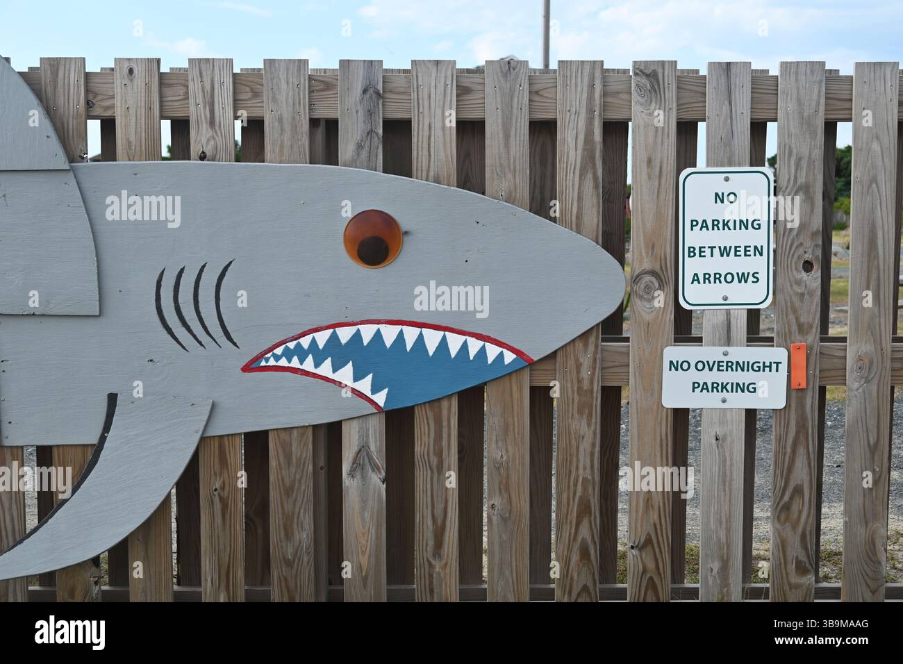 Une murale de requin sur une clôture pointe vers le panneau « no parking » à l'Avon Pier dans les Outer Banks de Caroline du Nord Banque D'Images