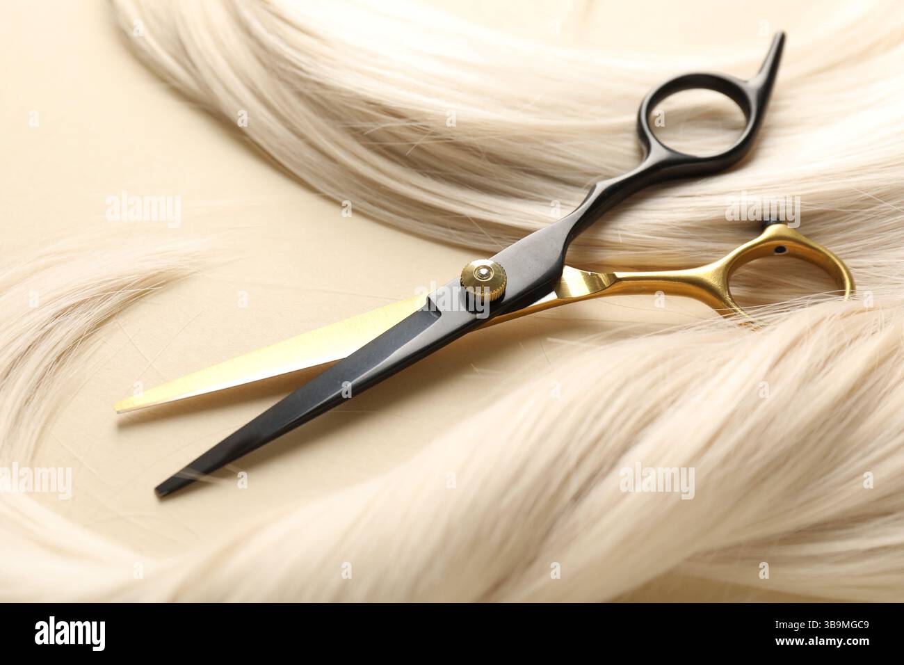 Mèches de cheveux et ciseaux sur fond beige, gros plan Banque D'Images