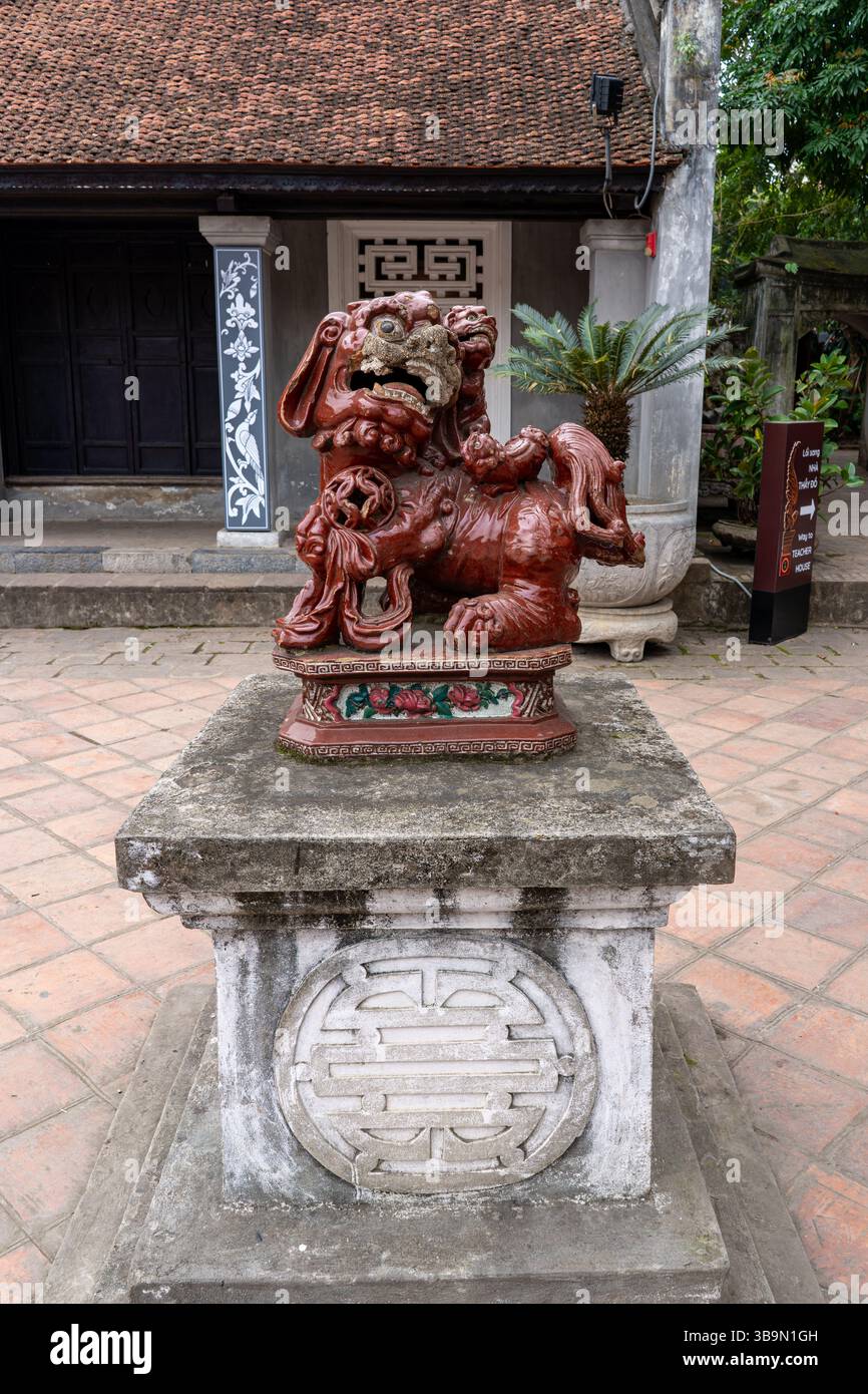 Une vue détaillée d'une sculpture vietnamienne traditionnelle, avec une figure de lion décorative sur un piédestal en pierre dans un cadre de temple. Banque D'Images