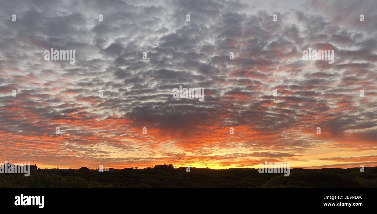 @Nuages brisés dans le coucher du soleil. Un coucher de soleil spectaculaire de l'Essex perçant à travers des nuages éparpillés, des faisceaux de lumière dorée ont percé le ciel et dansé à travers l'horizon. Les nuages superposés ajoutent de la profondeur et de la texture, transformant une soirée ordinaire en un moment de crainte tranquille. Banque D'Images