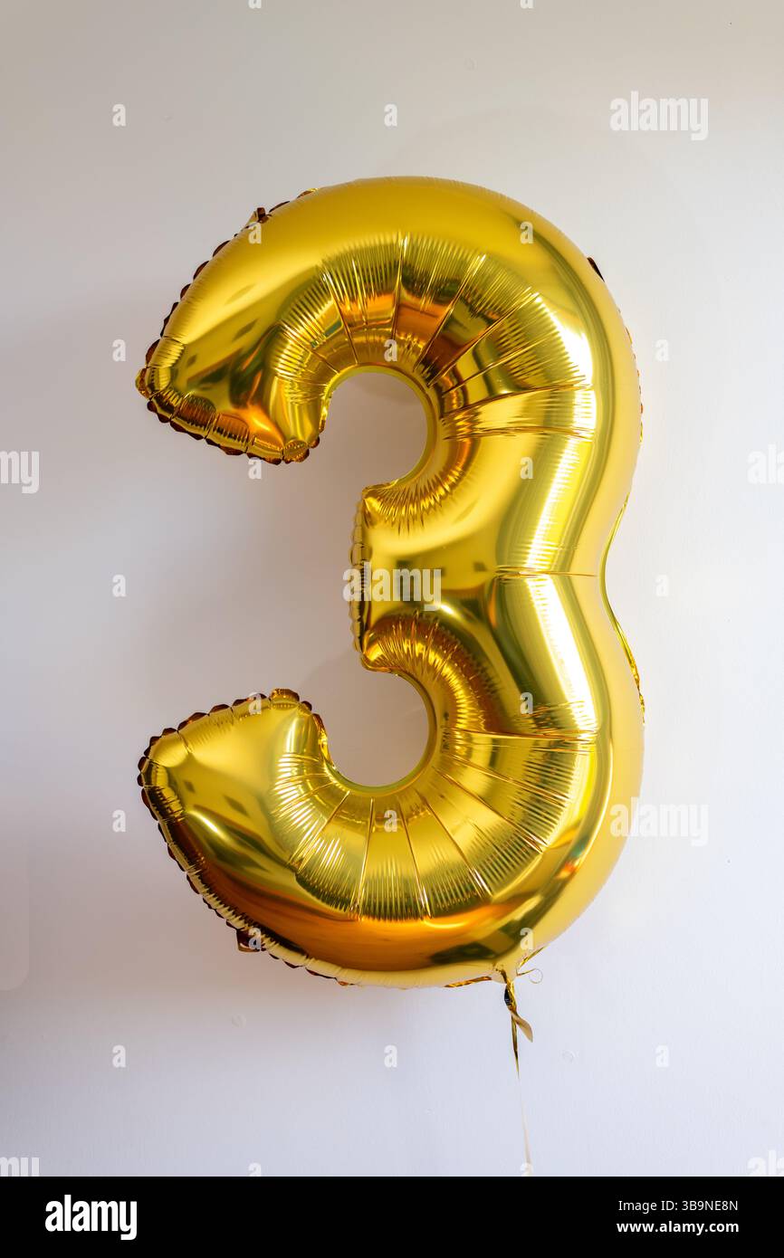 Ballon en feuille d'or en forme de numéro trois (3) Banque D'Images
