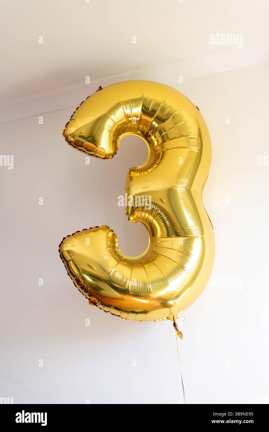 Ballon en feuille d'or en forme de numéro trois (3) Banque D'Images