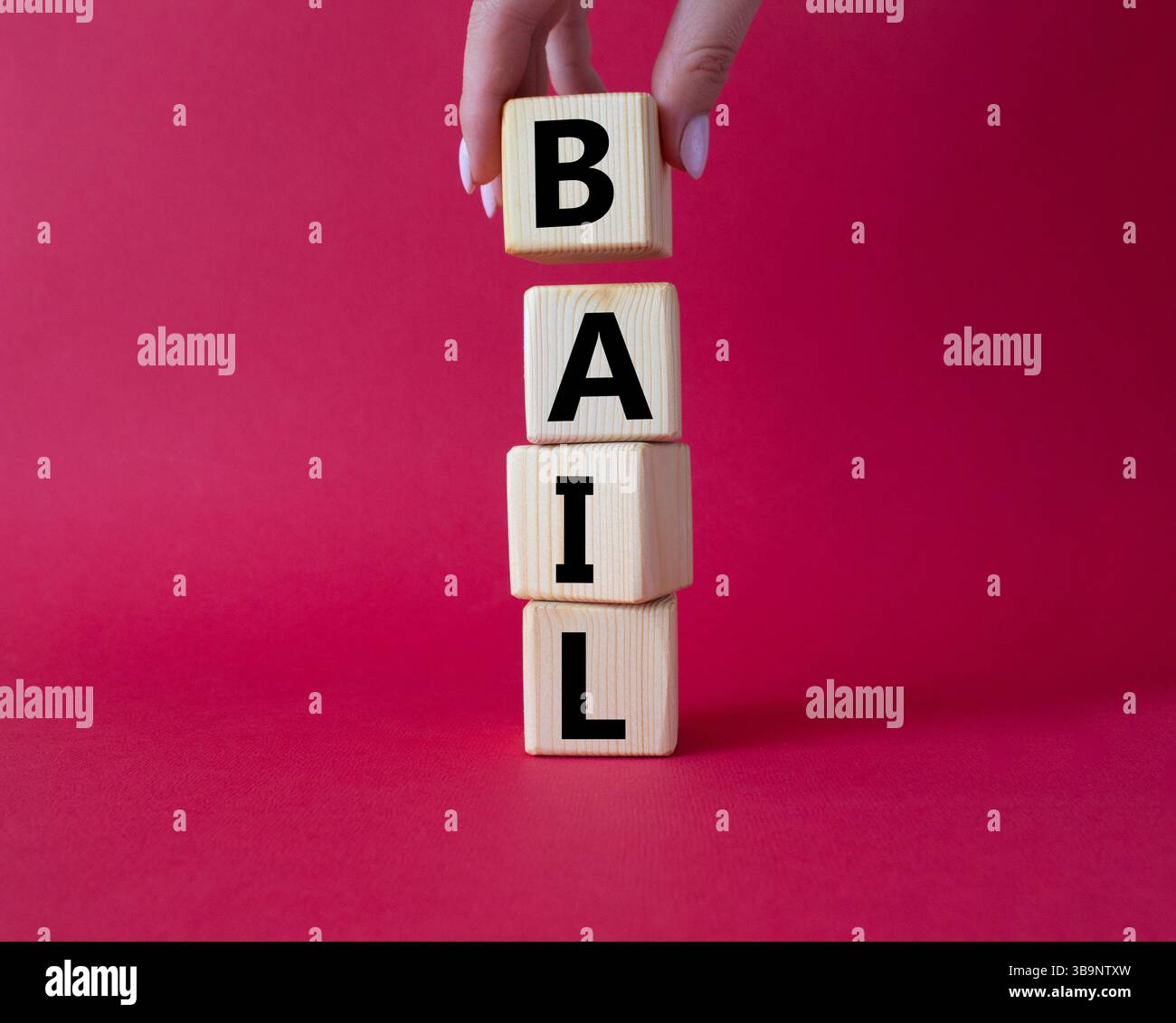 Symbole de béquille. Concept mot bail sur cubes en bois. Main d'homme d'affaires. Beau fond rouge. Business and bail concept. Copier l'espace. Banque D'Images