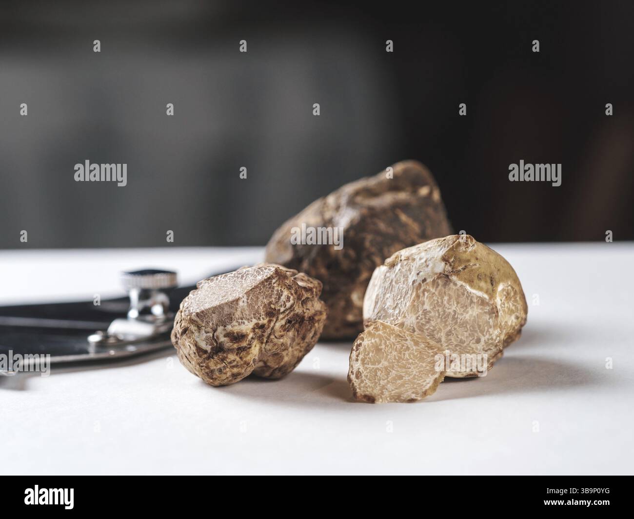 Truffes blanches chères champignons gourmands sur la table blanche à l'intérieur du restaurant. Rangée de truffes brunes avec tranche sur une table blanche avec backgrou foncé Banque D'Images