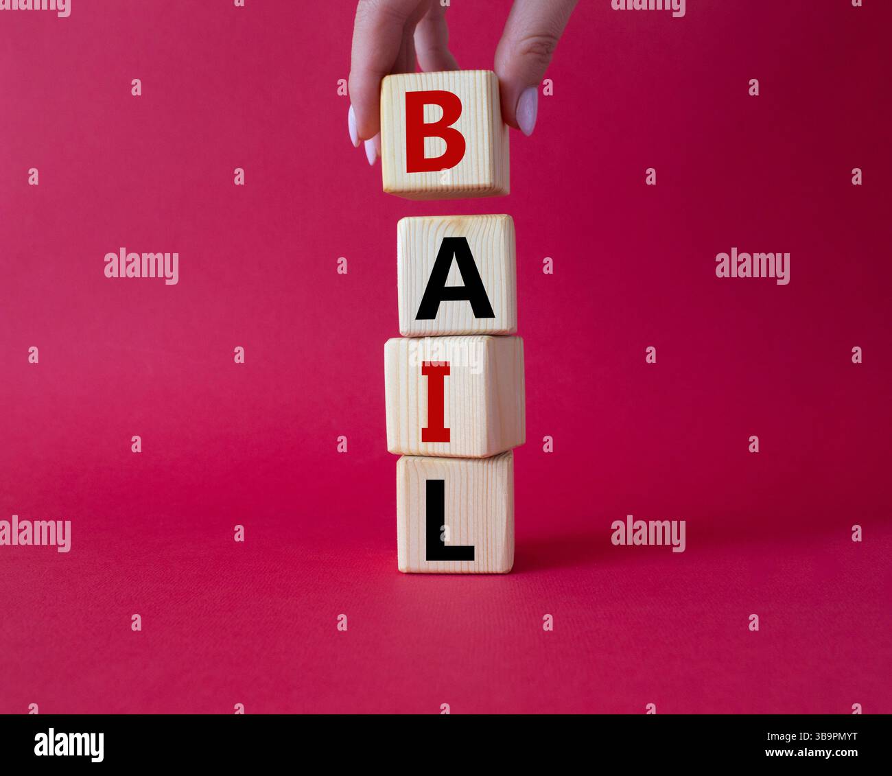 Symbole de béquille. Concept mot bail sur cubes en bois. Main d'homme d'affaires. Beau fond rouge. Business and bail concept. Copier l'espace. Banque D'Images