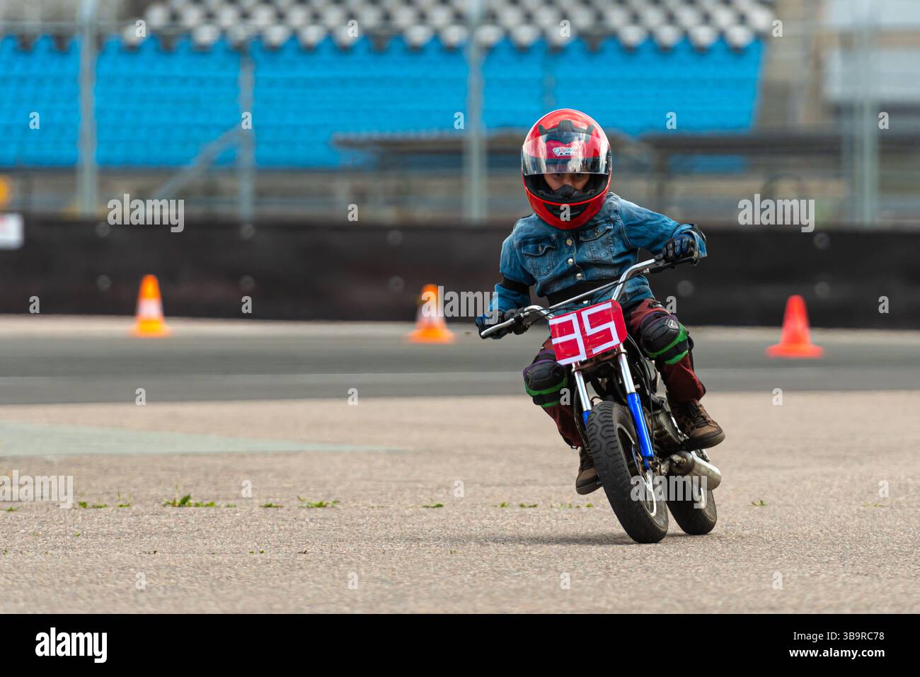 Riga, Lettonie - 3 juillet 2021 : un enfant pilote s'entraîne dans une formation de moto dans un centre de sport automobile avec des cônes d'entraînement. Banque D'Images
