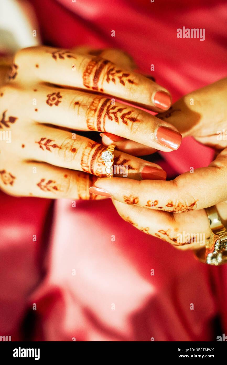 Une image en gros plan montrant les mains d'une femme ornées de motifs traditionnels de mehndi (henné) et portant une bague de fiançailles. Banque D'Images