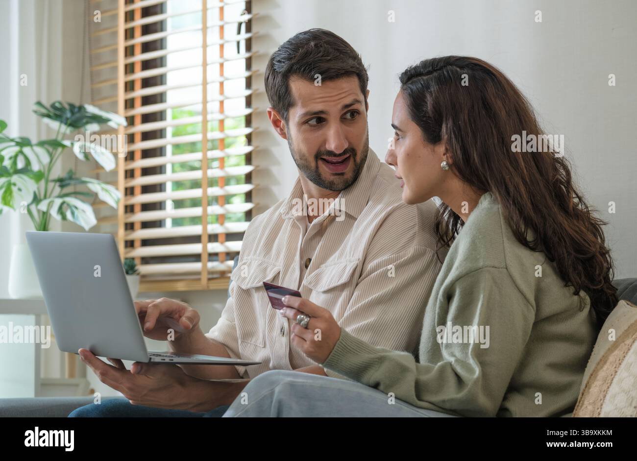 Couple hispanique utilisant un ordinateur portable et une carte de crédit pour magasiner en ligne via l'application e-commerce, faire le paiement et la navigation plate-forme moderne avec des codes promo et d Banque D'Images