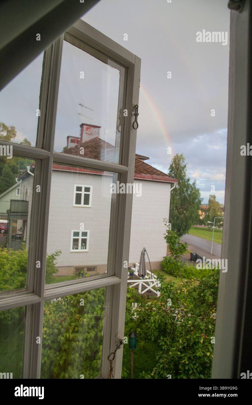 Fenêtre ouverte en été et un arc-en-ciel est visible sur le ciel gris Banque D'Images