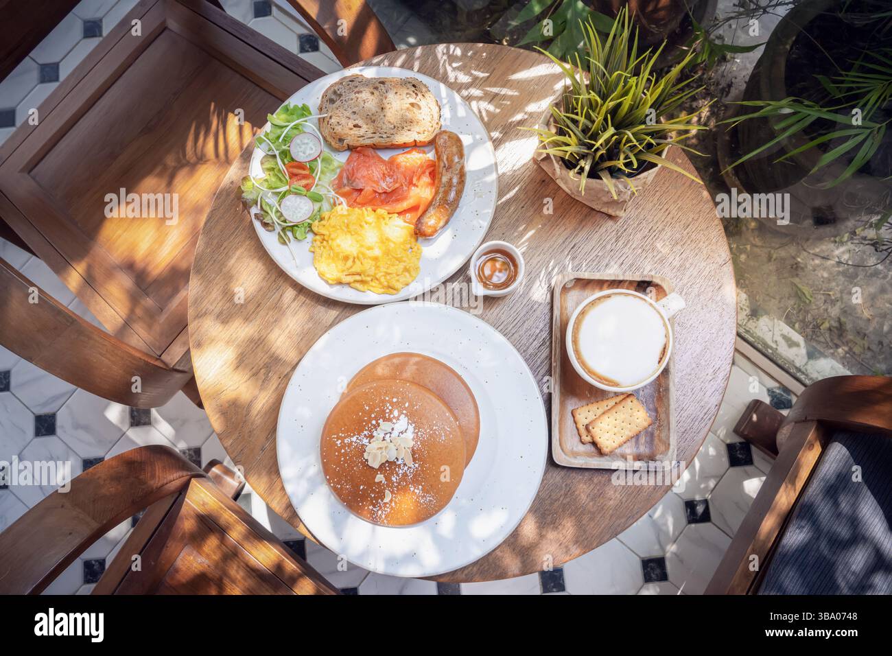 Un délicieux petit déjeuner est présenté sur une table en bois avec des piles de crêpes moelleuses surmontées de beurre, une portion d'œufs brouillés, saucisse, un Banque D'Images