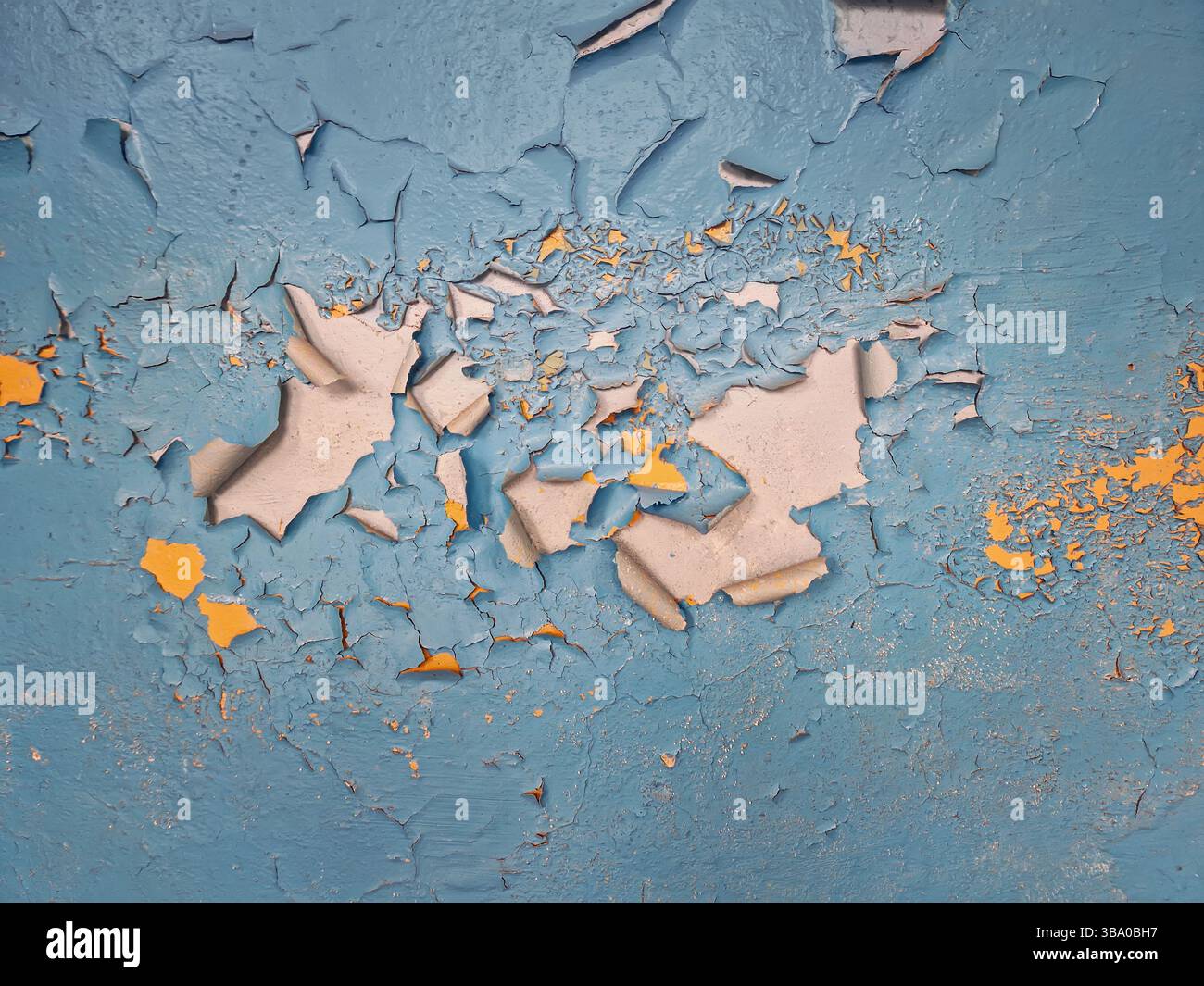 Gros plan sur le mur en béton avec peinture bleue pelable révélant des taches d'émail jaune en dessous. Vieillissement de fond de texture rugueuse, altération et détérioration - Image de stock capturée avec un smartphone