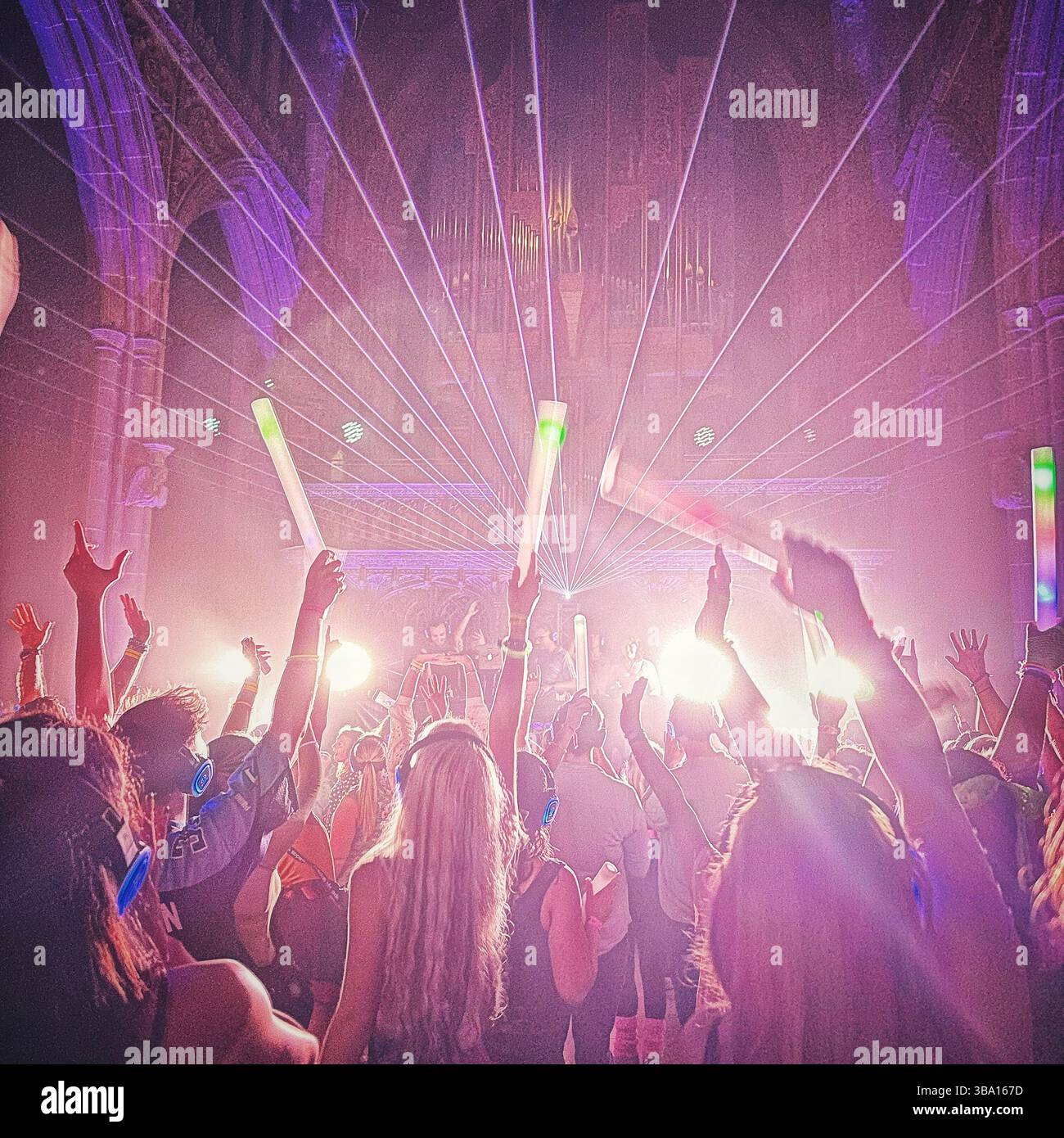 Silent Disco à l'intérieur de la cathédrale de Manchester avec des néons et une foule dansante, 18 août 2023. Les personnes portant des écouteurs et agitant des bâtons lumineux. Banque D'Images