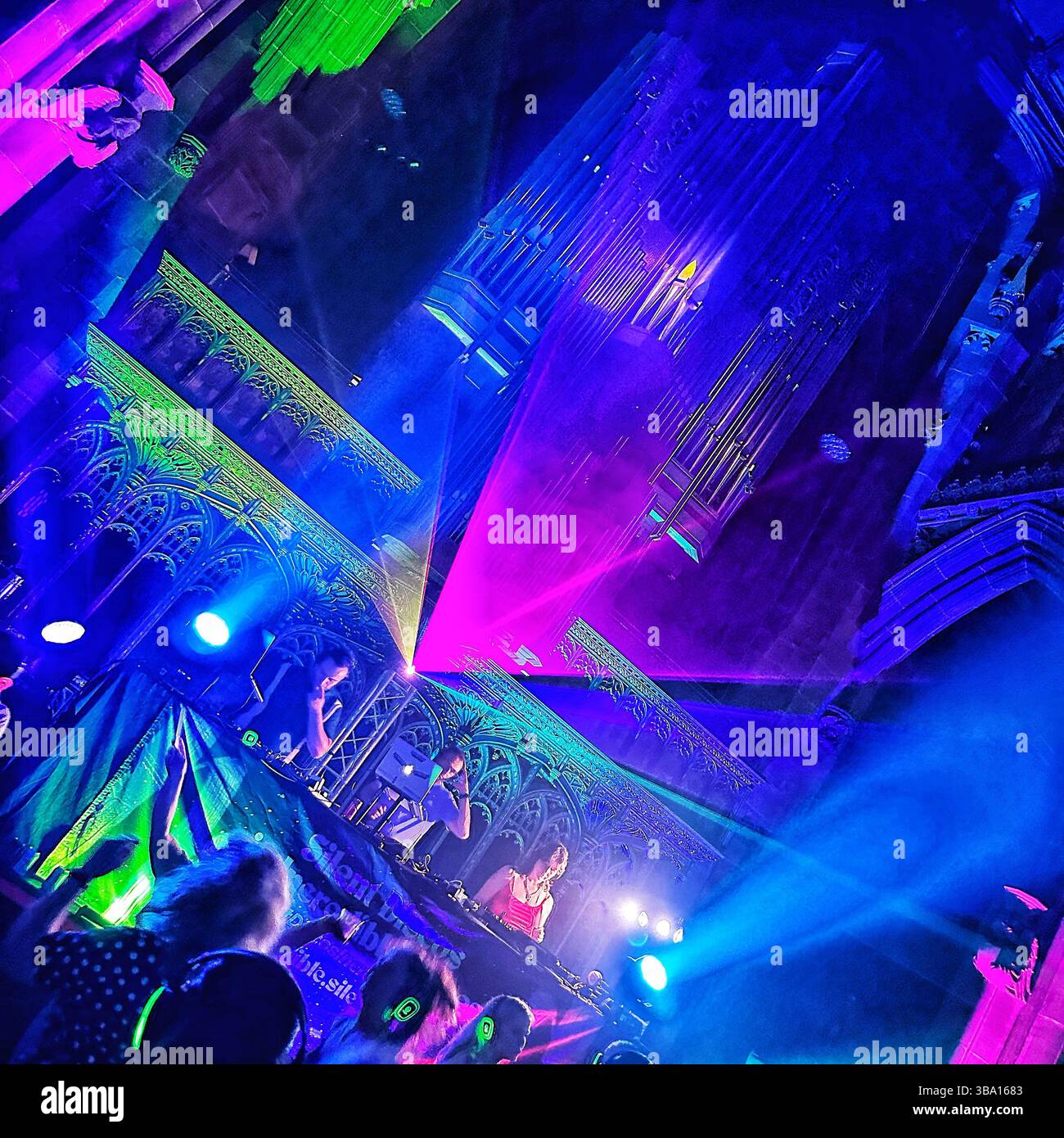Silent Disco à l'intérieur de la cathédrale de Manchester avec des néons et une foule dansante, 18 août 2023. Les personnes portant des écouteurs et agitant des bâtons lumineux. Banque D'Images