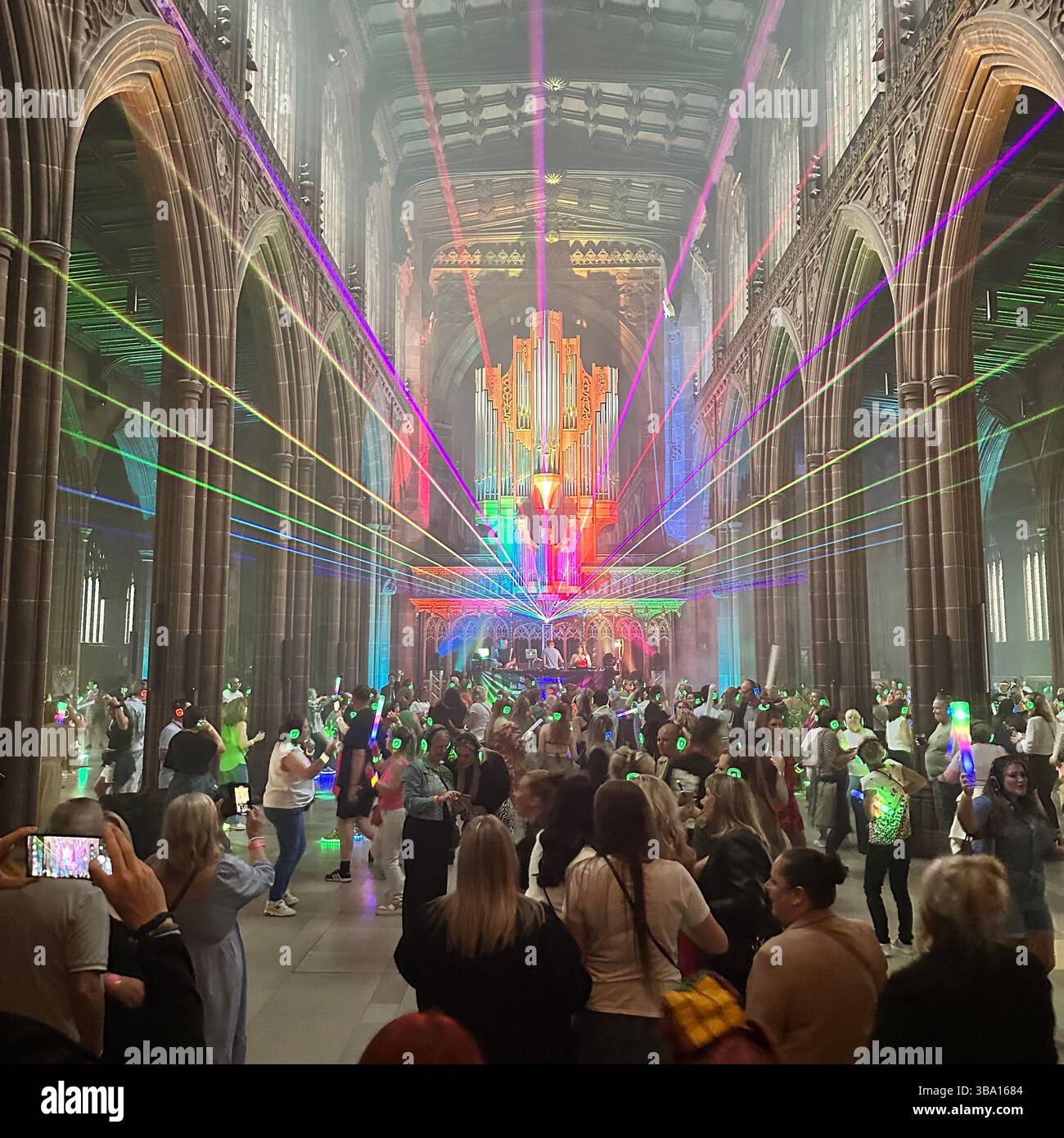 Silent Disco à l'intérieur de la cathédrale de Manchester avec des néons et une foule dansante, 18 août 2023. Les personnes portant des écouteurs et agitant des bâtons lumineux. Banque D'Images