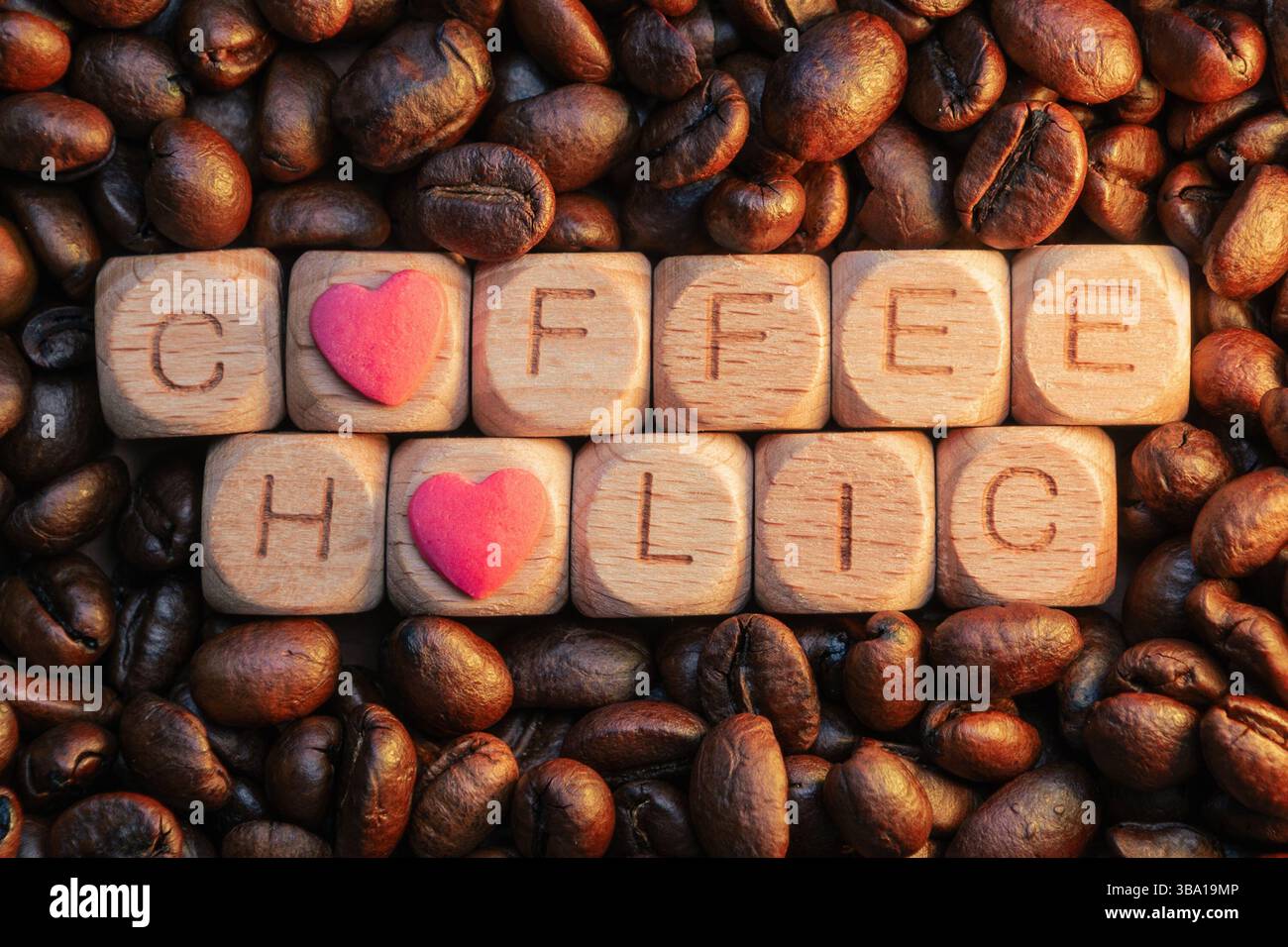 Message Coffeeholic avec des blocs de bois et des accents de coeur entourés de grains de café. Banque D'Images