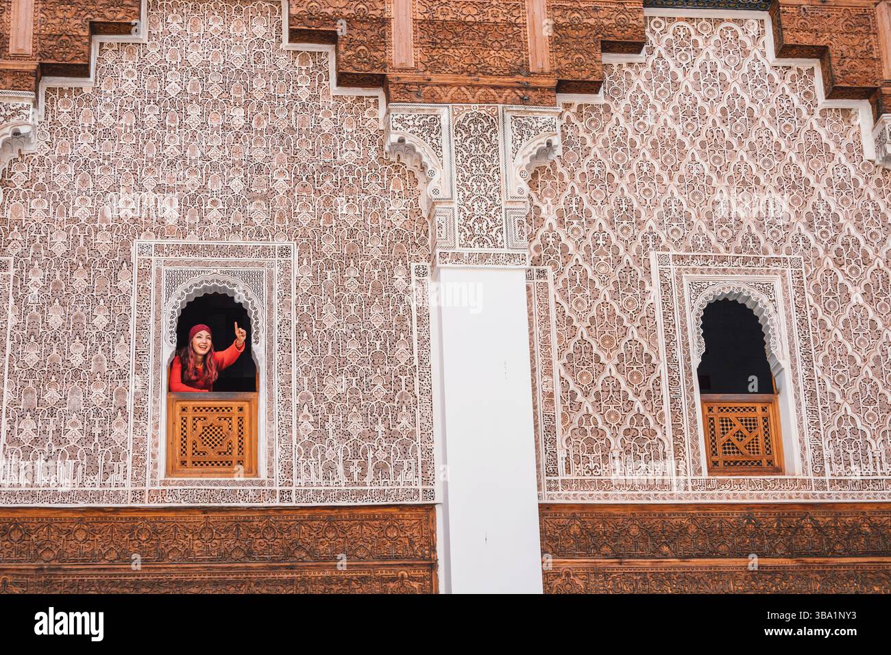 Jeune femme pointant son doigt vers le haut lors de la visite de la belle Madrasa Ben Youssef à Marrakech, Maroc Banque D'Images