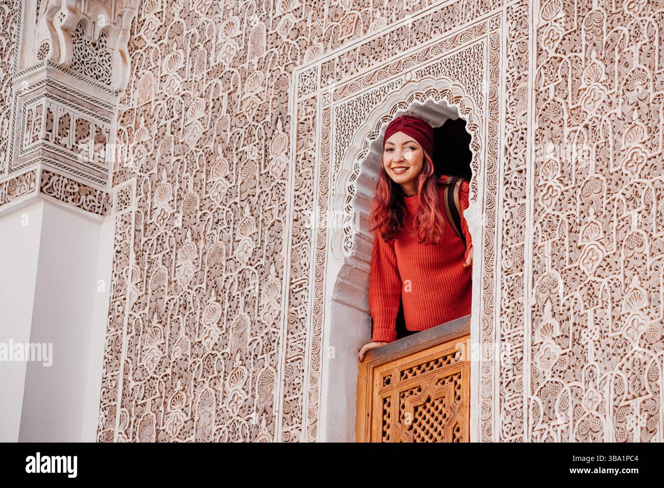 Jeune femme regardant par une fenêtre la Madrasa Ben Youssef à Marrakech, Maroc Banque D'Images