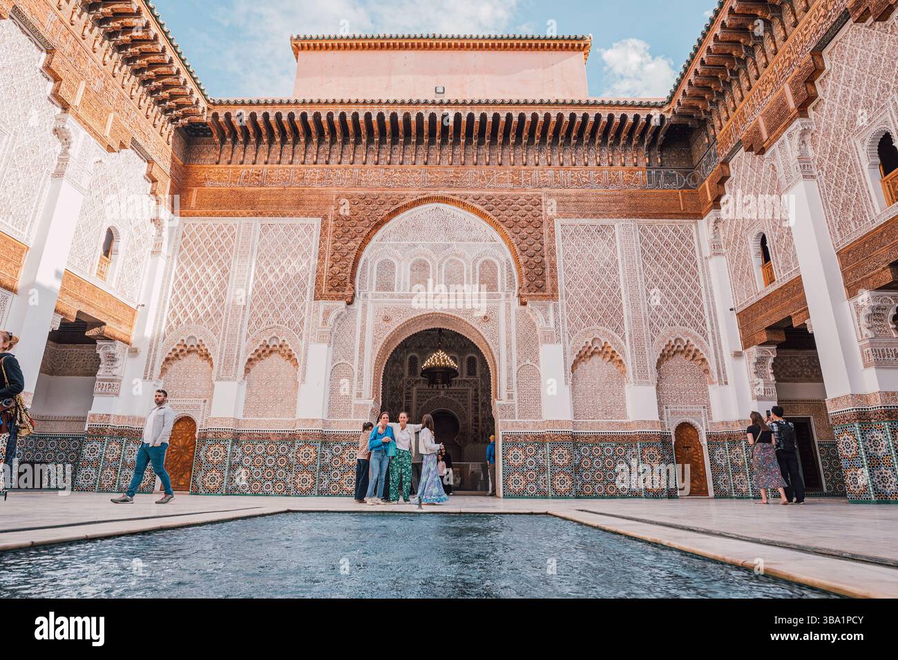 06 mars 2025, Marrakech, Maroc : touristes visitant la cour avec la piscine centrale de la Madrasa Ben Youssef Banque D'Images