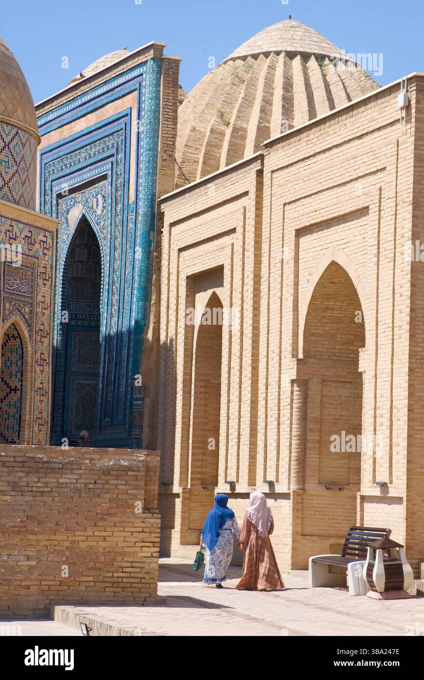 Deux femmes en tenue traditionnelle marchant par les entrées voûtées des mausolées de la nécropole de Shah-i-Zinda, Samarcande, Ouzbékistan Banque D'Images