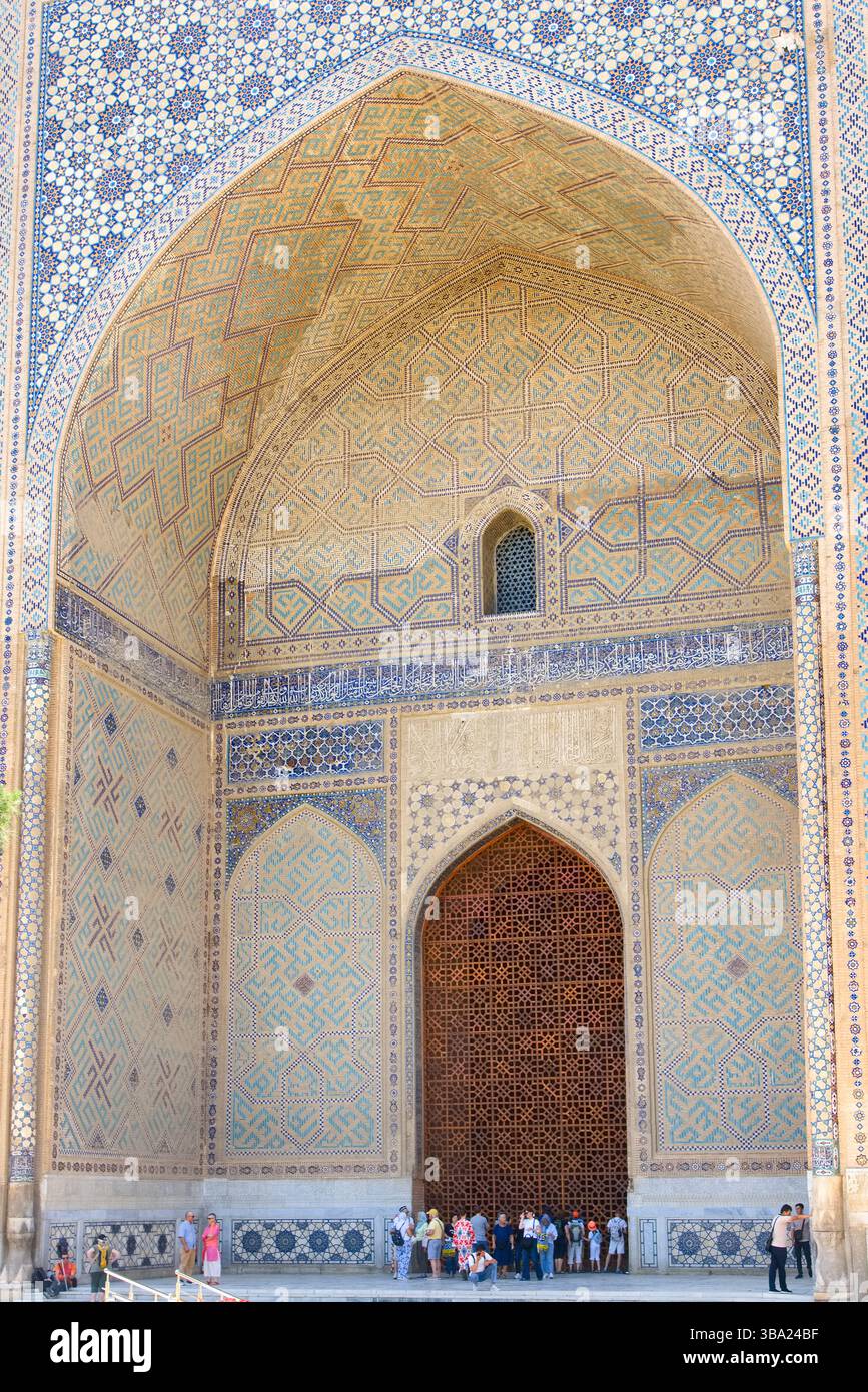 Touristes et fidèles devant l'immense entrée voûtée de la mosquée Bibi-Khanym à Samarcande Ouzbékistan Banque D'Images