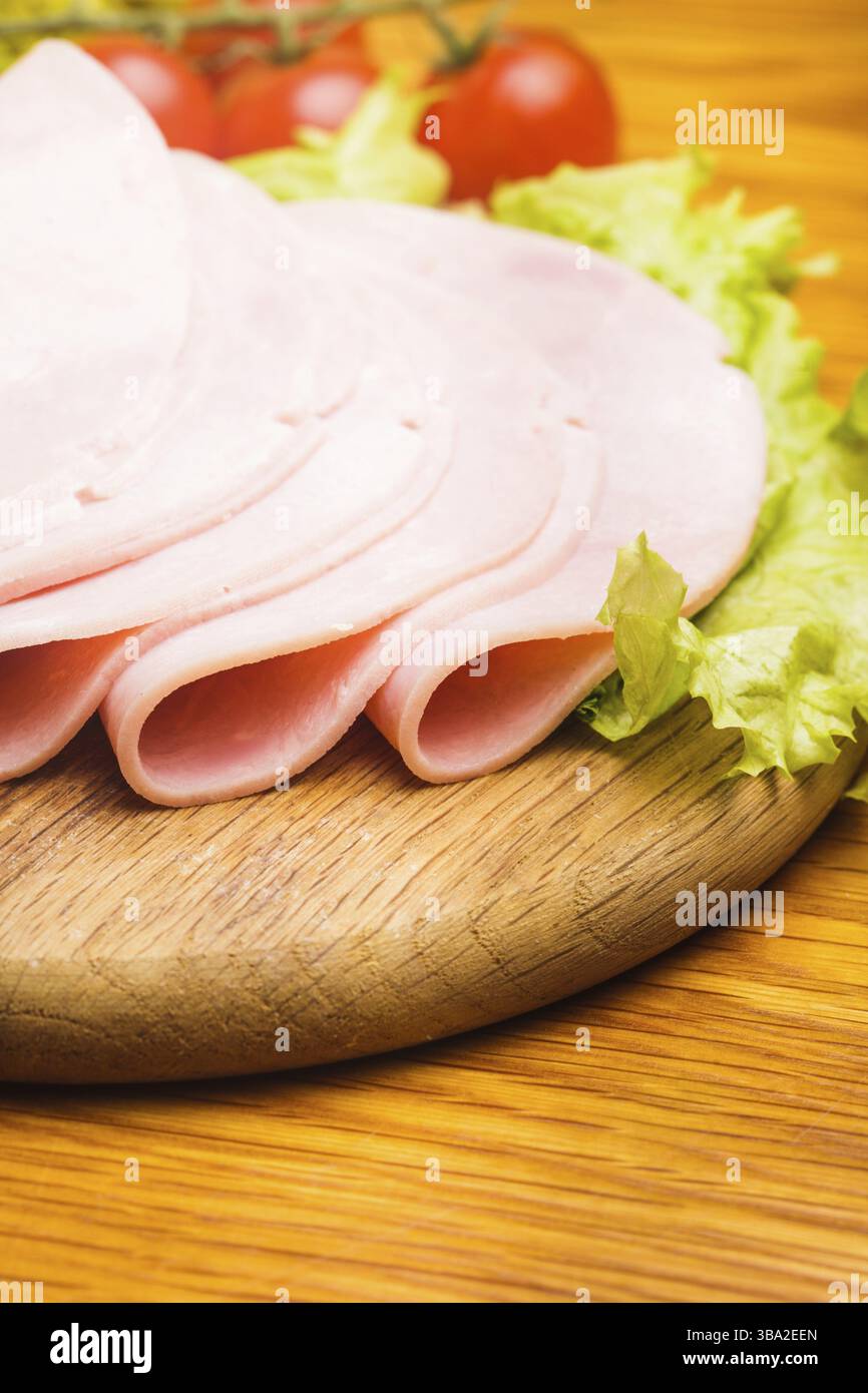 Tranches de jambon frais avec lattuce et tomate cerise sur la planche de bois Banque D'Images Tranches de jambon frais avec lattuce et tomate cerise sur la planche de bois Banque D'Images