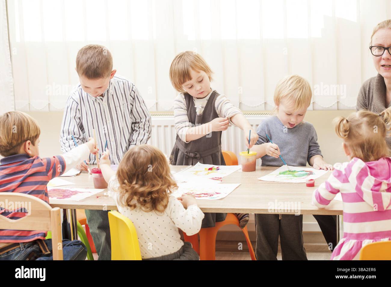 Les enfants et le tuteur sont la peinture à l'aide d'un pinceau et d'aquarelles sur papier dans le jardin d'enfants Banque D'Images