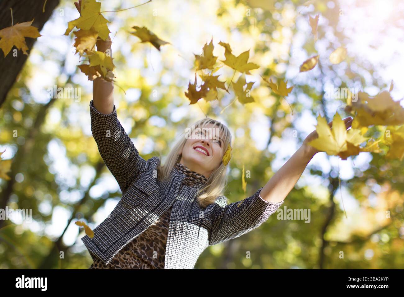 Femme jette les feuilles d'automne dans le parc Banque D'Images