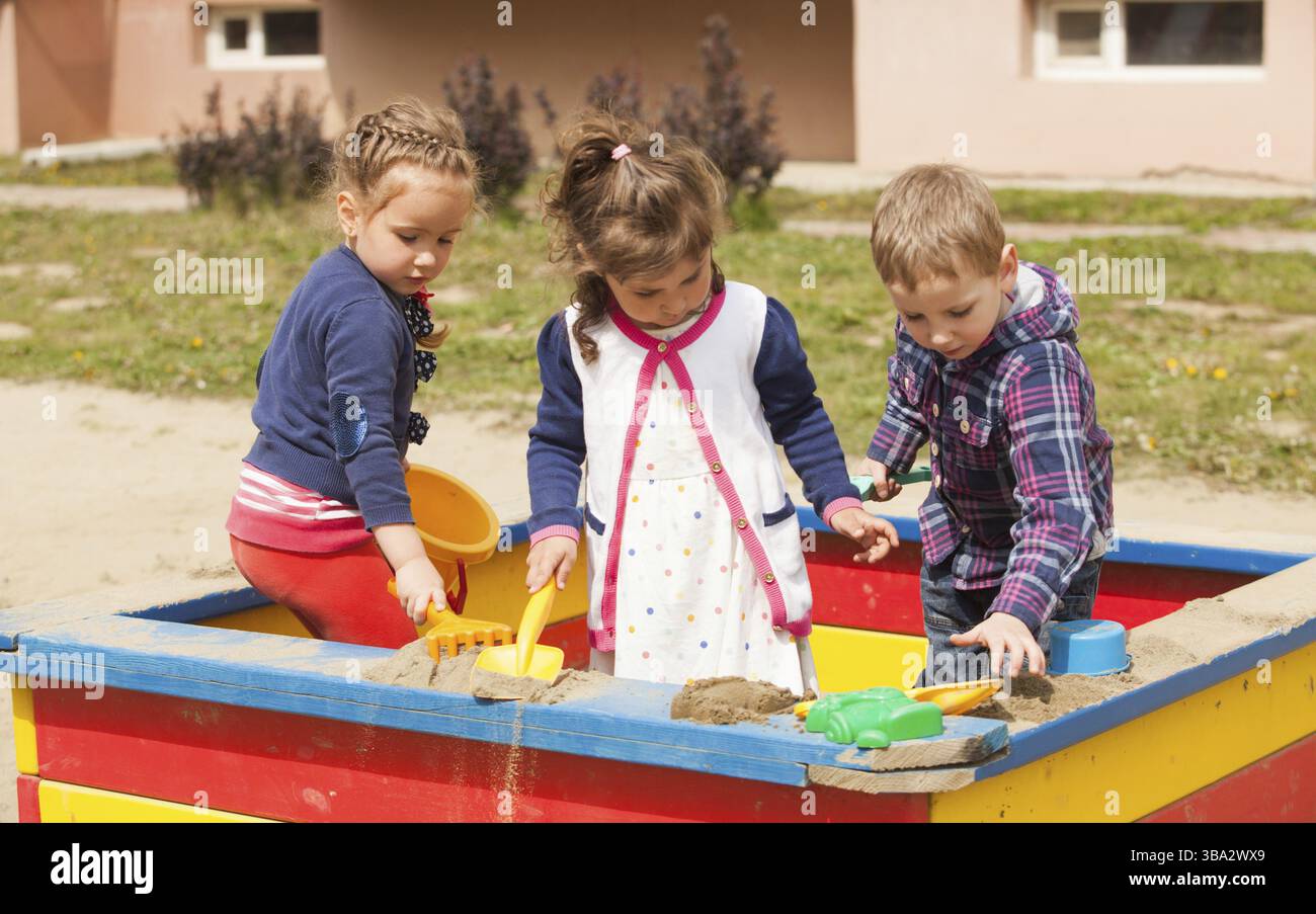 Des enfants jouent dans l'aire de jeux avec du sable dans le bac à sable Banque D'Images