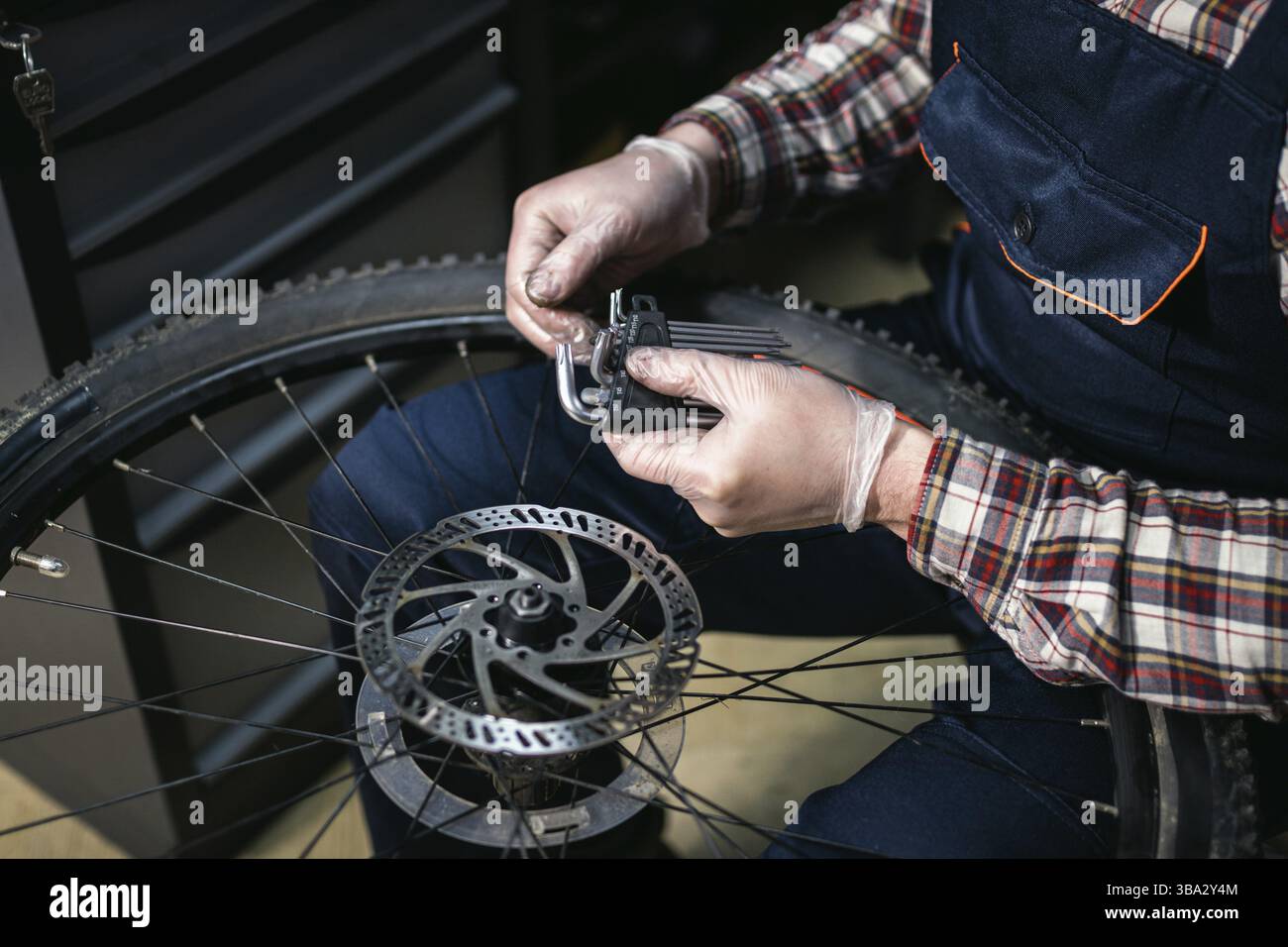Homme mécanicien travaillant dans un atelier de réparation de vélos, mécanicien réparant le vélo à l'aide d'un outil spécial, portant des gants de protection. Jeune fixin de technicien de maintenance attrayant Banque D'Images
