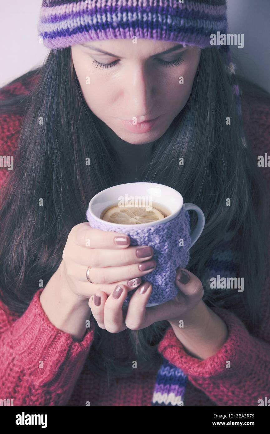 La femme tient une tasse de thé tricotée avec du citron Banque D'Images
