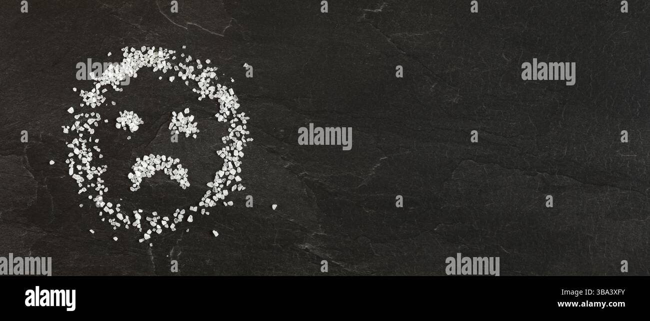 Émoticône de visage triste faite de cristaux de sel, photo large d'en haut - bannière avec espace pour le texte à droite. Concept malsain de suralting, Liptovsky Hradok, Banque D'Images