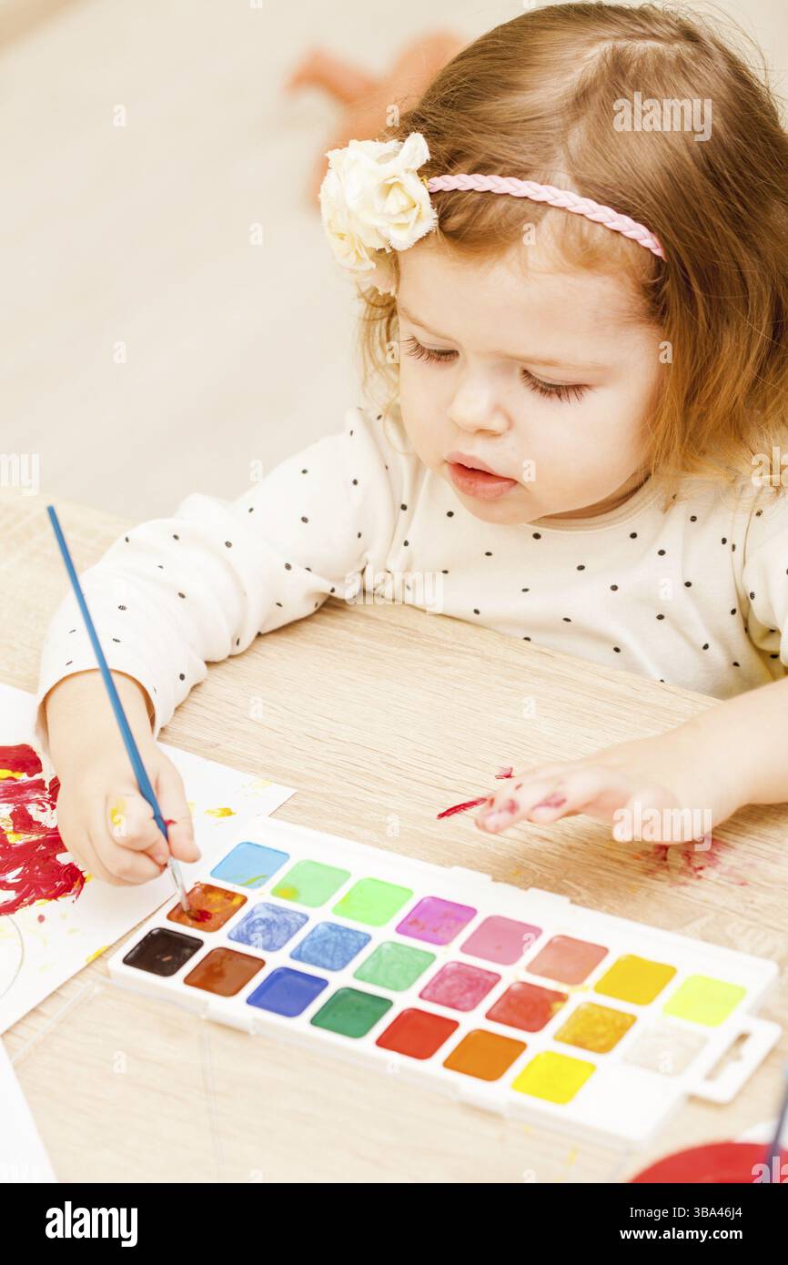 Fille, c'est peindre avec un pinceau et d'aquarelles sur papier dans le jardin d'enfants Banque D'Images