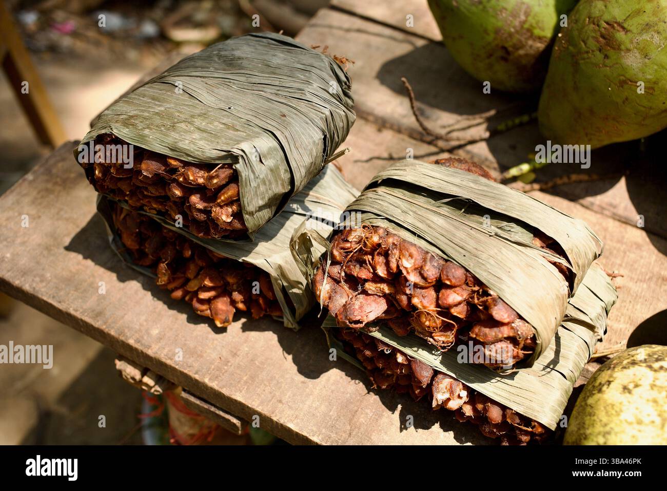 Paquets de tamarin et noix de coco vertes sur un stand en bord de route à Bandarban, Chittagong Hill Tracts, Bangladesh, enveloppés dans un emballage de feuilles séchées. Banque D'Images