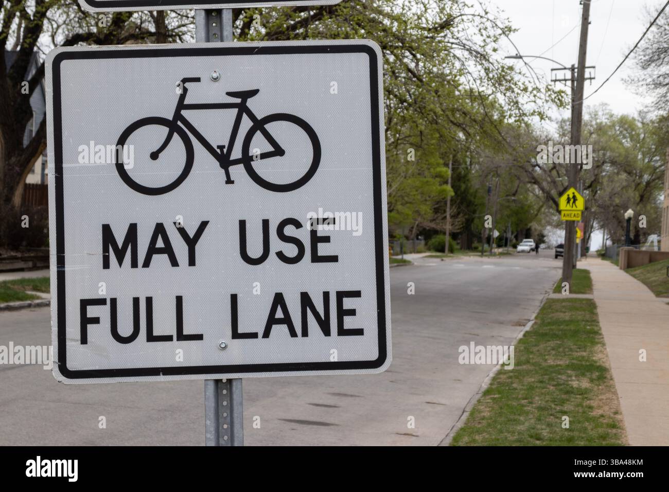 Un panneau près d'une rue résidentielle à Omaha, Nebraska, États-Unis, indique aux automobilistes que les vélos peuvent utiliser la voie pleine. Message pour la sécurité routière pour les cyclistes. Banque D'Images
