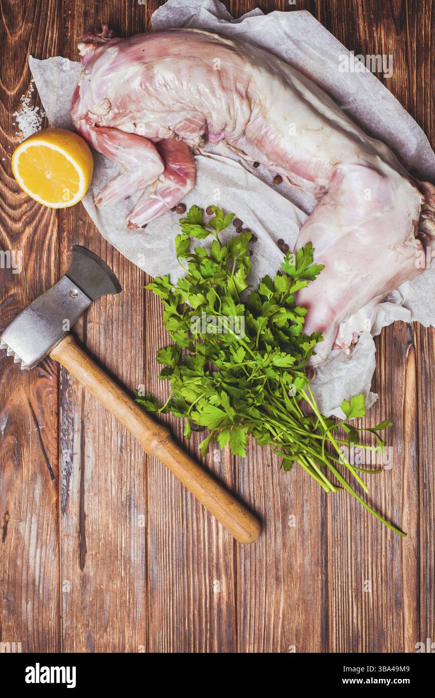 Viande de lapin crue avec citron, sel et persil sur fond de bois Banque D'Images