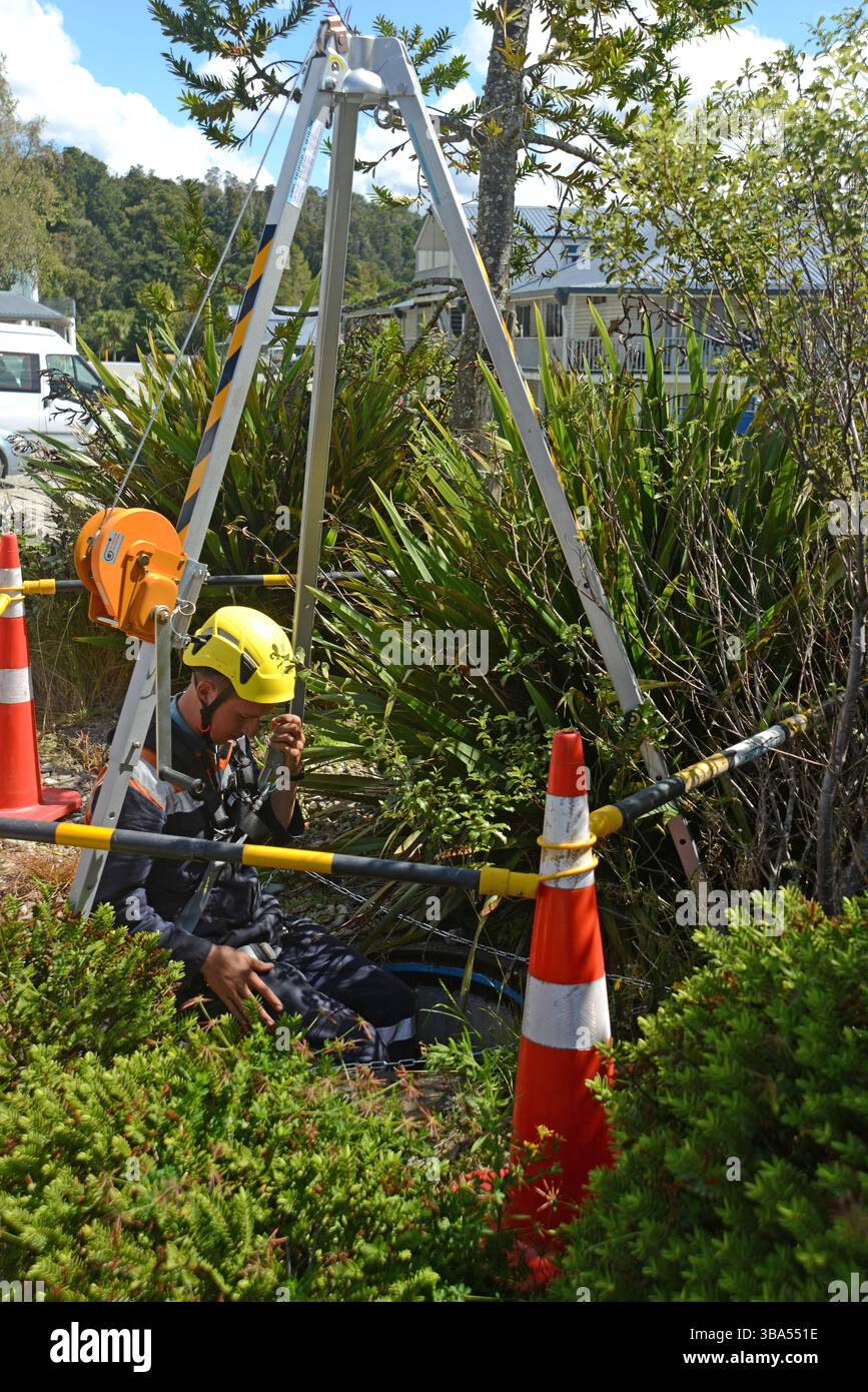 Un apprenti plombier pénètre dans un espace confiné pour un exercice d'entraînement dans un drain d'eaux pluviales sur une propriété commerciale Banque D'Images