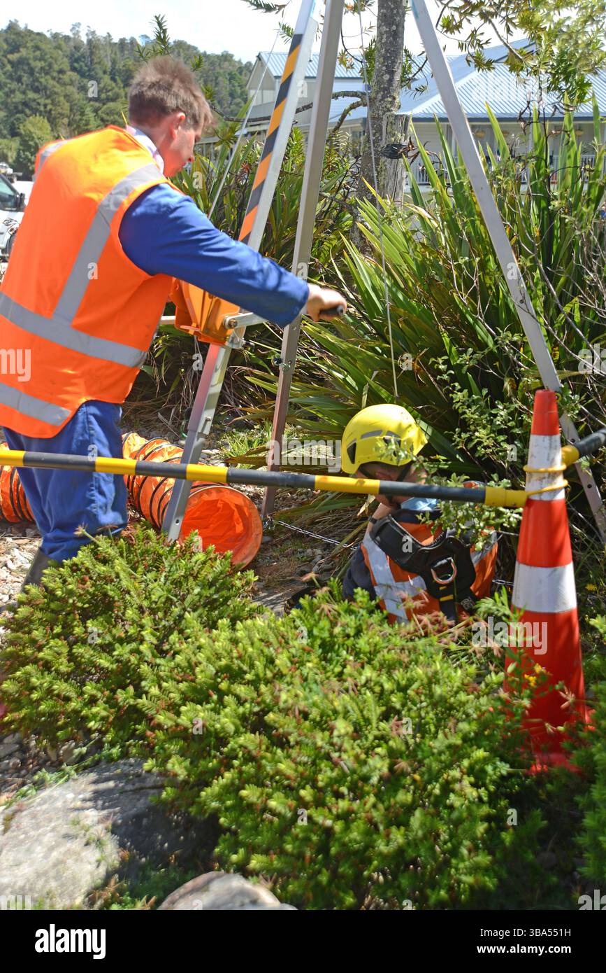 Un apprenti plombier pénètre dans un espace confiné pour un exercice d'entraînement dans un drain d'eaux pluviales sur une propriété commerciale Banque D'Images