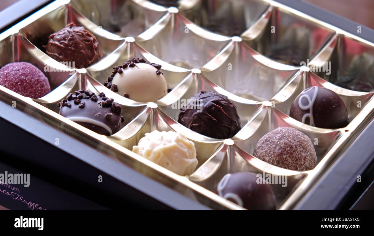 Tirelire rose avec des pièces de choco sur fond noir Banque D'Images