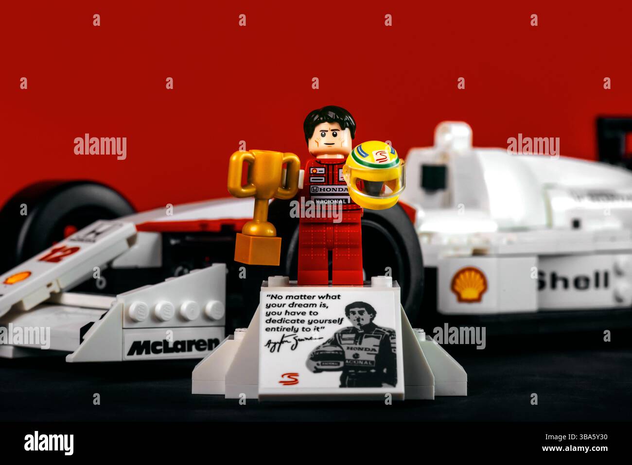 Ayrton Senna Lego figure pilote de formule 1 brésilien à côté de sa voiture de formule 1 McLaren MP4/4 sur un fond rouge.Editorial illustratif Banque D'Images