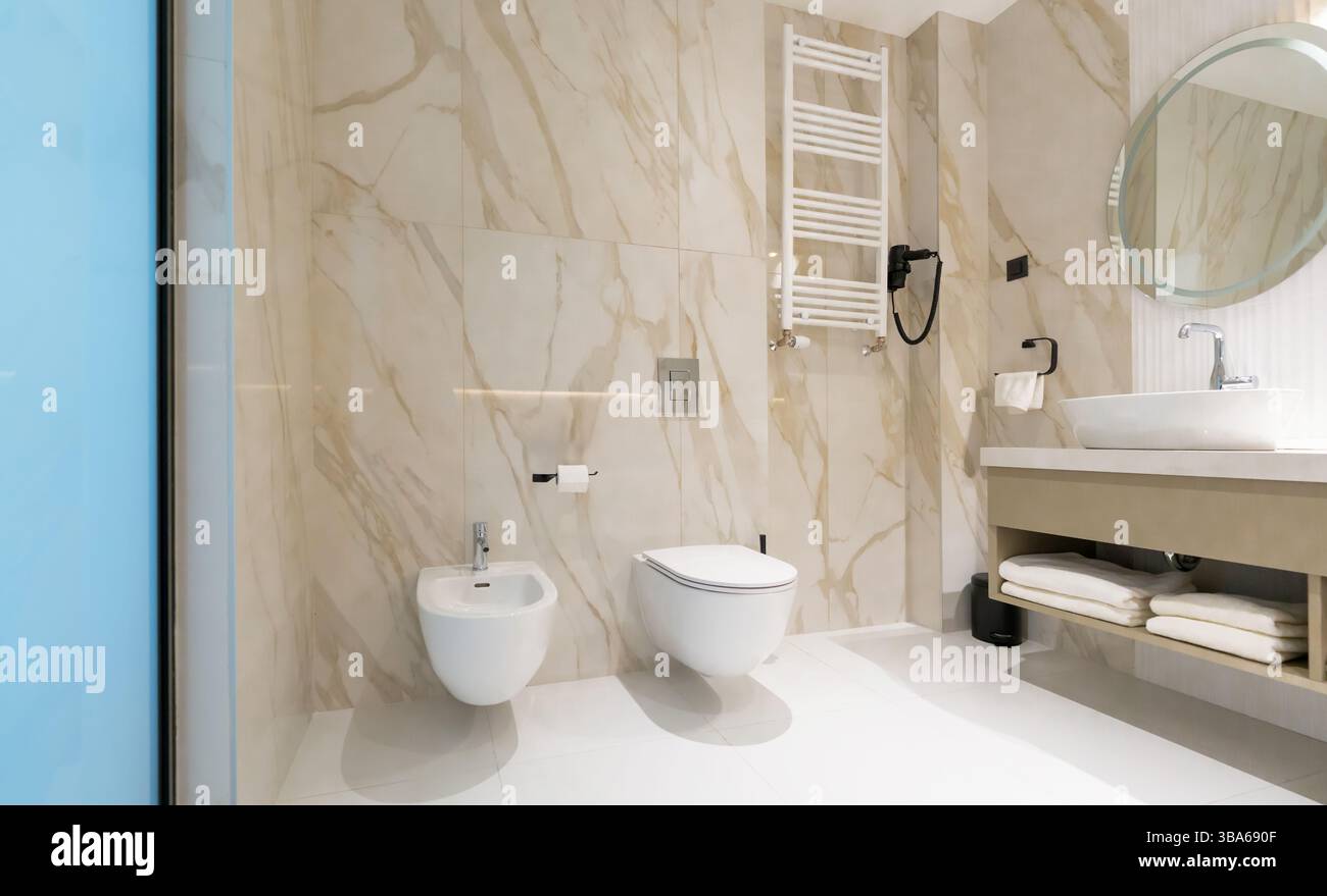 Une salle de bains moderne et propre avec toilettes, bidet et lavabo dans un élégant intérieur en marbre Banque D'Images