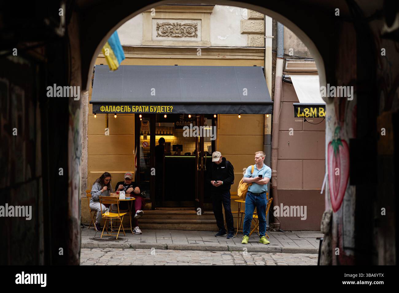 Lviv, Ukraine - 04 mai 2025 : un extérieur de magasin de falafel confortable avec des gens appréciant la nourriture et debout à proximité à Lviv, Ukraine. Banque D'Images