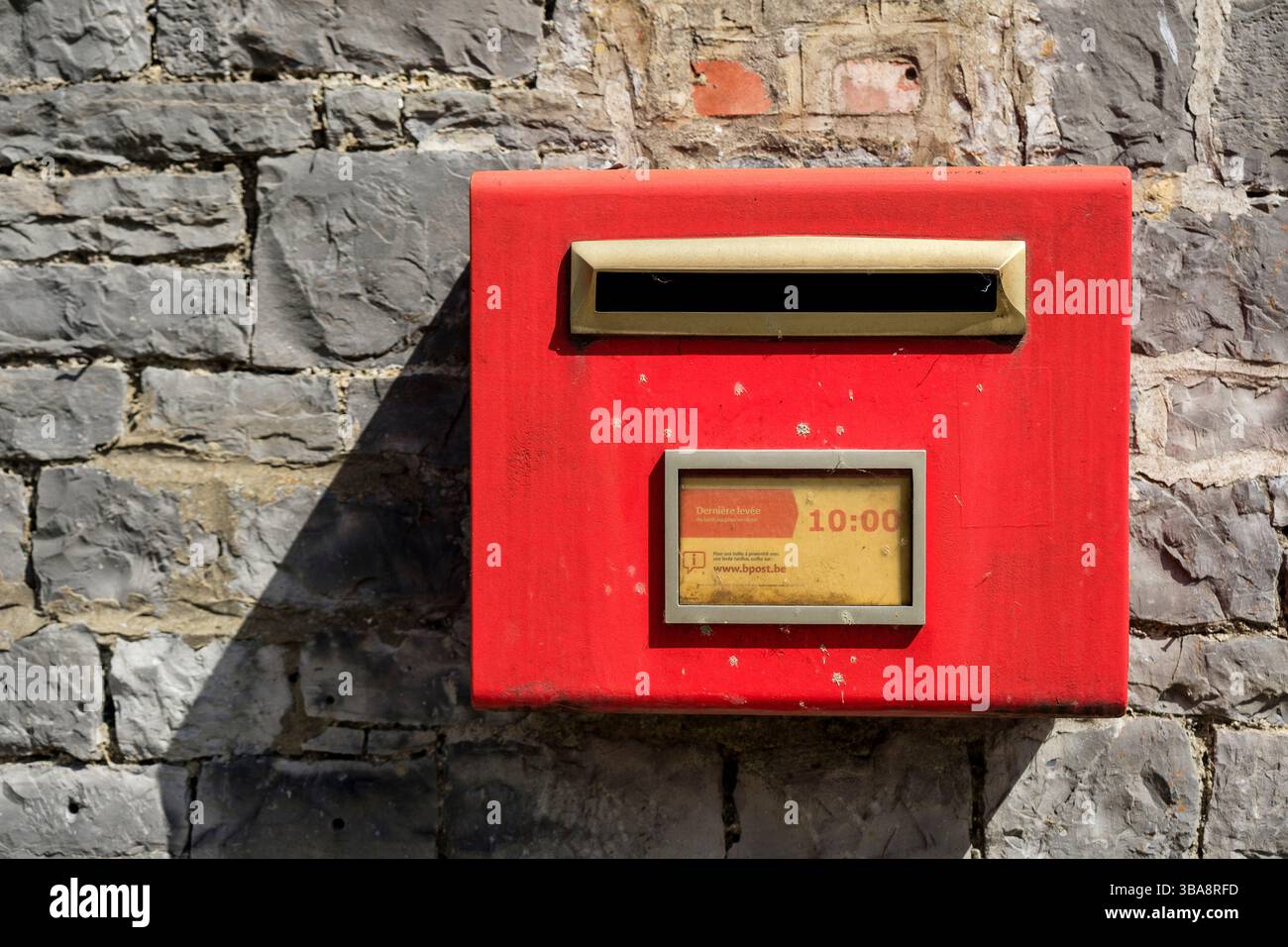 Boîte aux lettres rouge bpost belge sur crochet d'une rue de village | Boîte aux lettres belge dans uen rue de village Banque D'Images