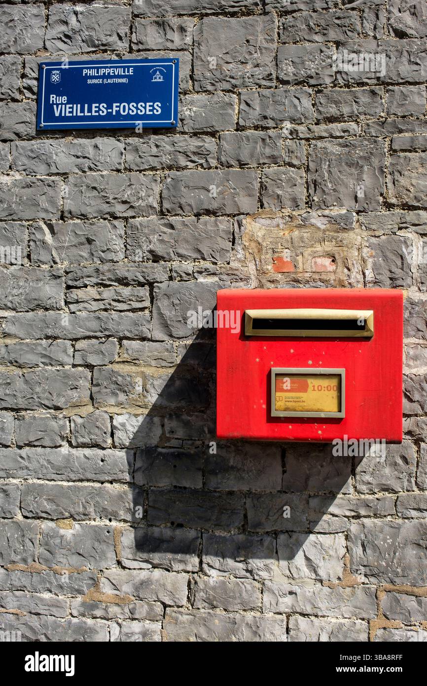 Boîte aux lettres rouge bpost belge sur crochet d'une rue de village | Boîte aux lettres belge dans uen rue de village Banque D'Images