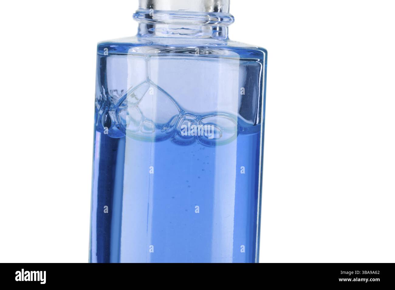 Partie d'une bouteille avec le liquide cosmétique bleu gros plan sur un fond blanc Banque D'Images