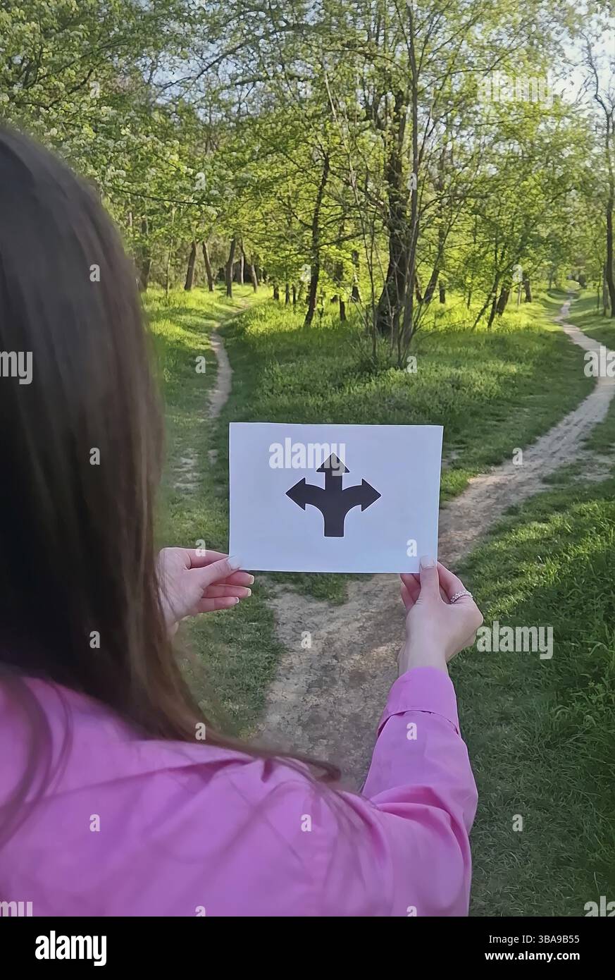 Mains de femme tenant un papier avec des flèches pointant vers la gauche, la droite et les directions droites blanches debout devant un carrefour. Symbole de chemin bifurqué pour d. Banque D'Images