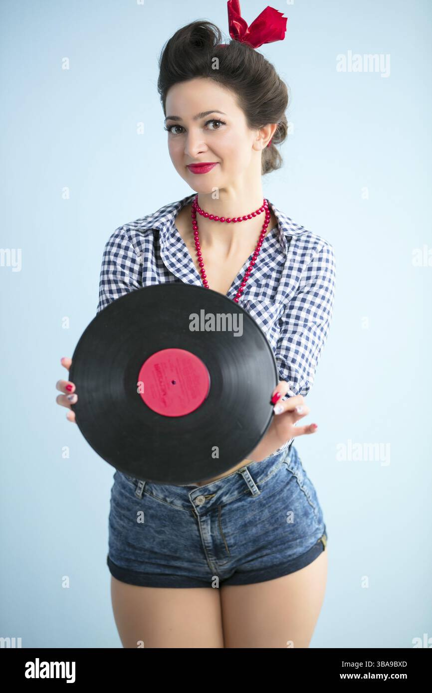 Rétro womanRetro femme dans le style des années cinquante tenant un disque de musique.n dans le style des années cinquante tenant un disque de musique Banque D'Images