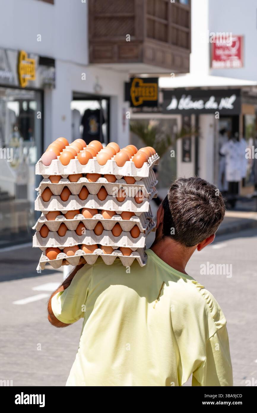 Espagne. Un homme marchant le long d'une rue en équilibrant des plateaux empilés d'œufs frais sur son épaule. Il porte six plateaux contenant chacun trente œufs. Banque D'Images