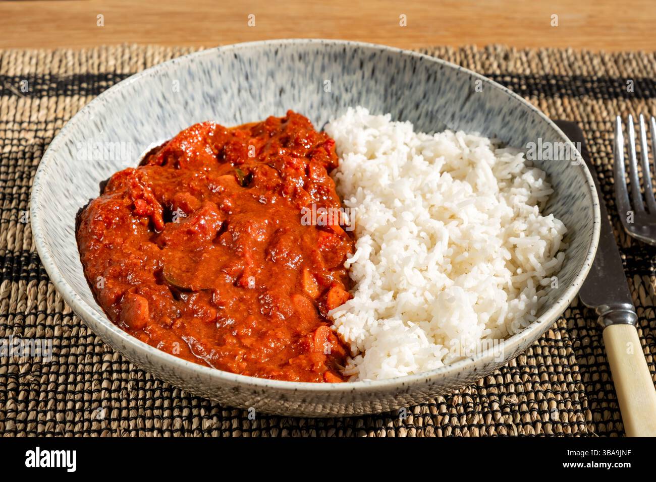 ROYAUME-UNI. Un curry de poulet au piment fait maison servi dans un bol avec du riz Basmati nature. Banque D'Images