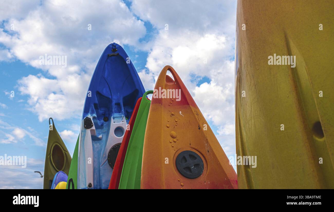 Groupe de planches à paddle de différentes tailles debout dans leur rack contre un fond de ciel bleu avec des nuages en angleterre Banque D'Images