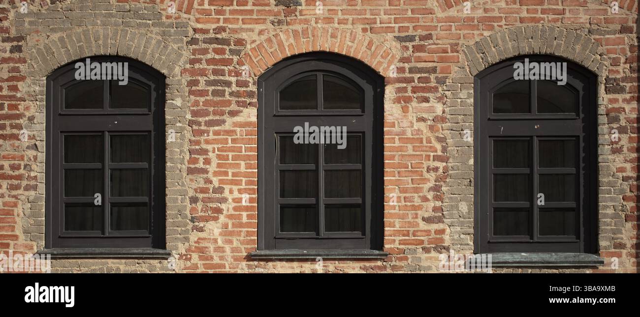 Mur de briques d'un ancien bâtiment avec fenêtres cintrées Banque D'Images
